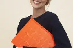 smiling woman standing while holding orange folder