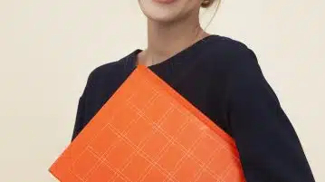 smiling woman standing while holding orange folder