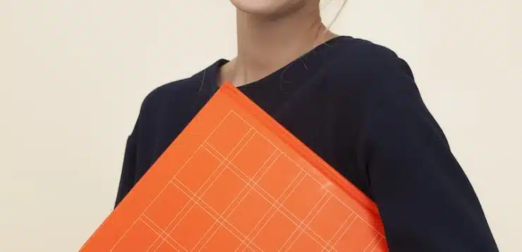 smiling woman standing while holding orange folder